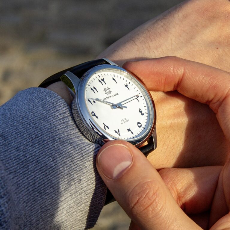 Montre ALWAQT Maison ZAFIR avec cadran blanc et bracelet en cuir noir portée au poignet.